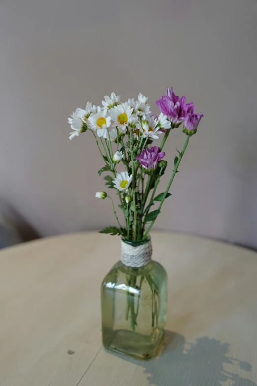 a jar with some daisies and other flowers in it