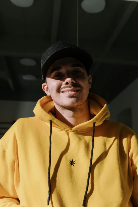 a man with a cap is wearing a yellow sweatshirt