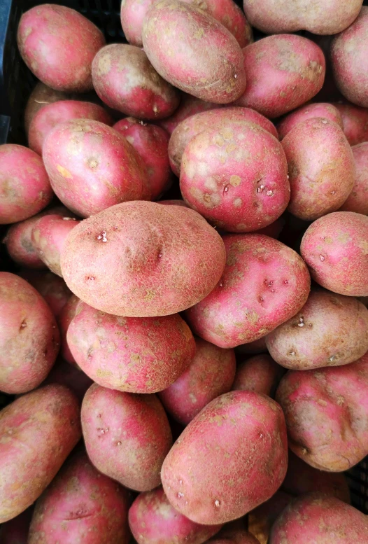 a pile of many red potatoes sitting on top of a table