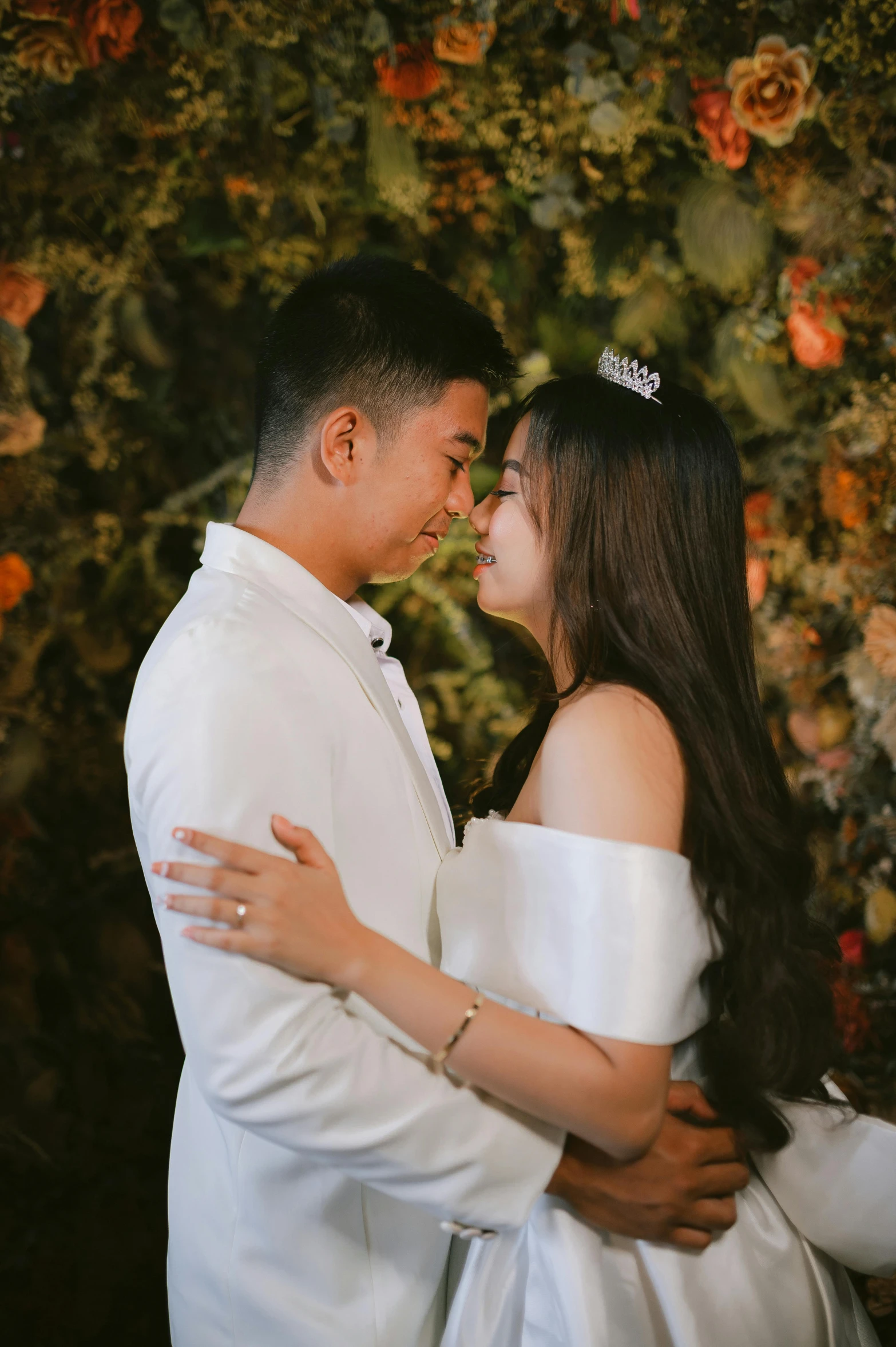 a man and woman emcing in front of flowers