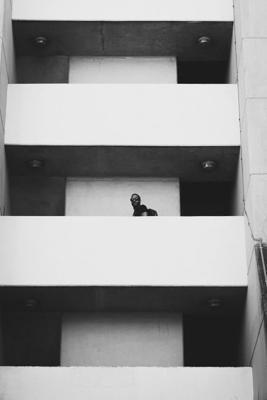 a black and white po of a person standing on the balcony of a building