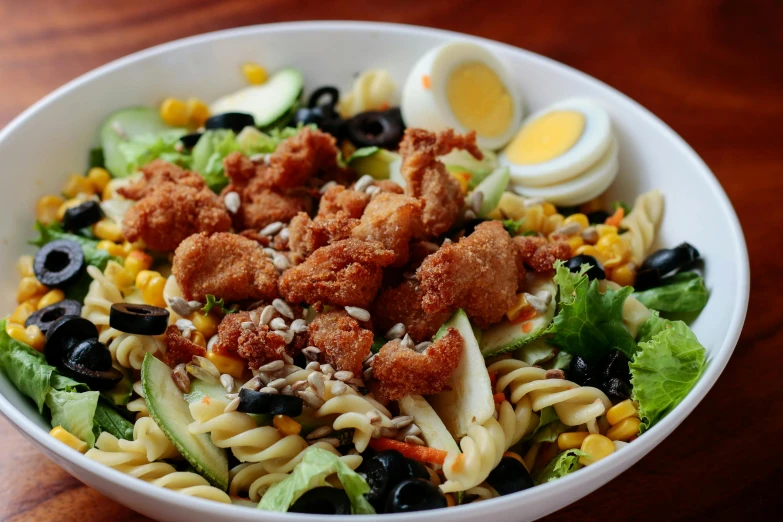 a salad with meat, tomatoes, cheese and other foods is displayed in a bowl