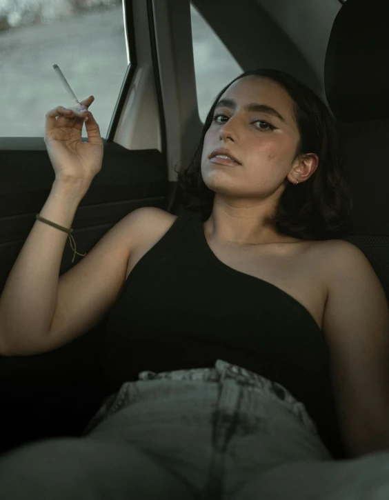 a woman is sitting in a car smoking a cigarette
