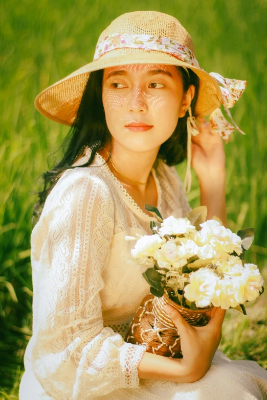 a woman holding a bouquet of flowers sitting in grass