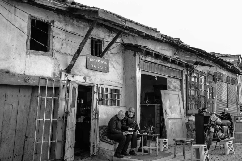 a man sits in front of a run down store