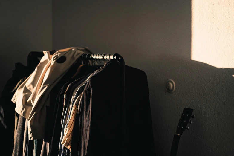 a suit rack filled with clothes against a wall