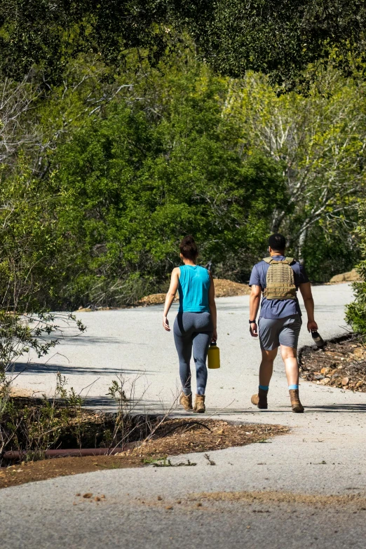 two people walking in the middle of a forest