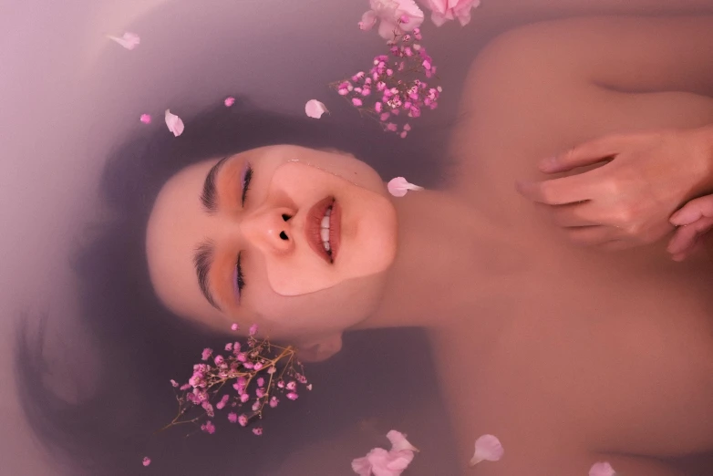 an asian woman is floating in the water with flowers