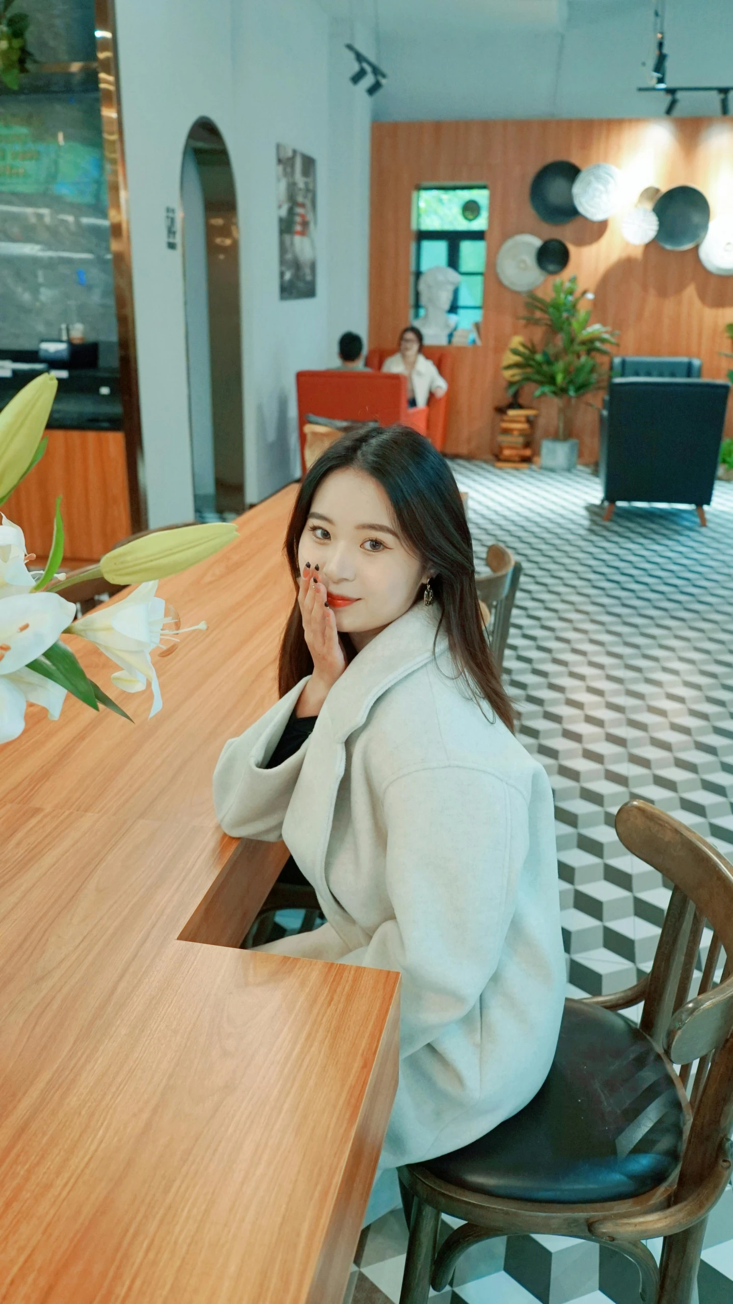 a woman sitting at a table with flowers on the side