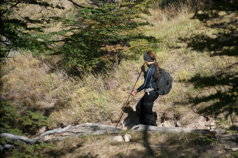 the young man is hiking up a hill with his backpack