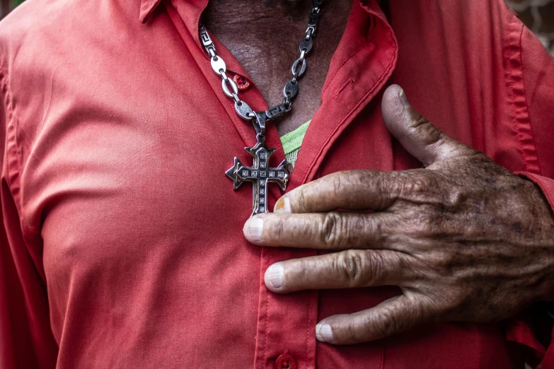 a man in a red shirt holding his cross necklace