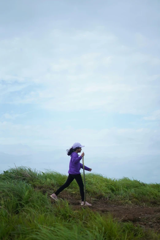 a woman standing on top of a lush green hillside