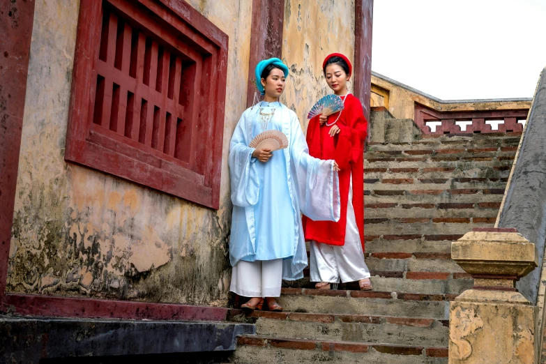 two women wearing traditional clothing are standing on some stairs