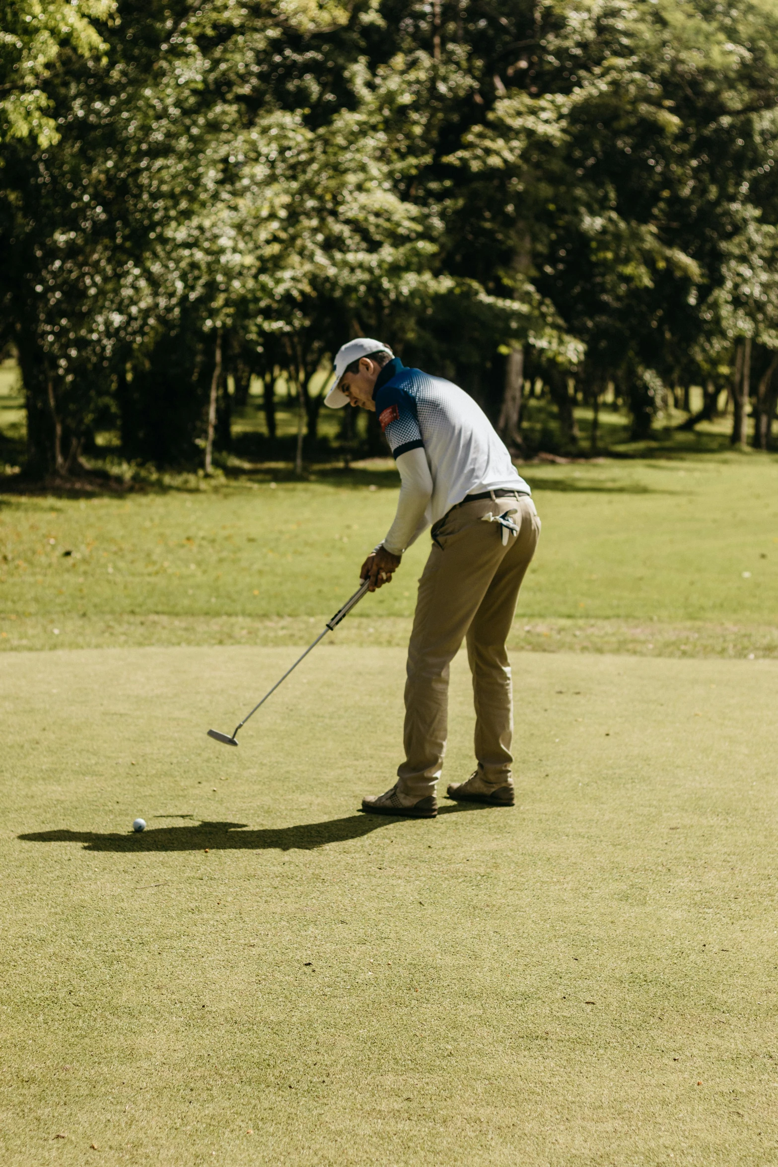 a person holding a golf club on a grassy course