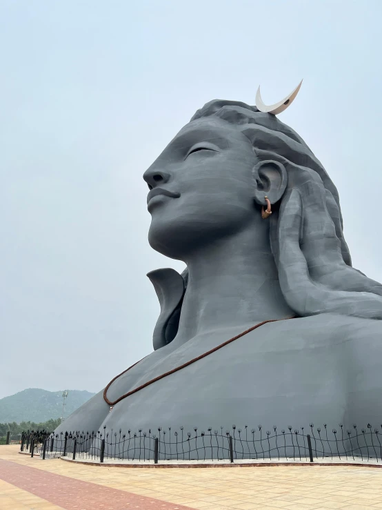 a huge statue with a woman's head up against a blue sky