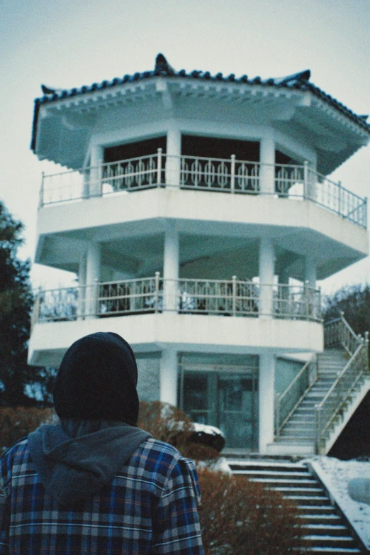 a person standing outside of a white building with an open roof