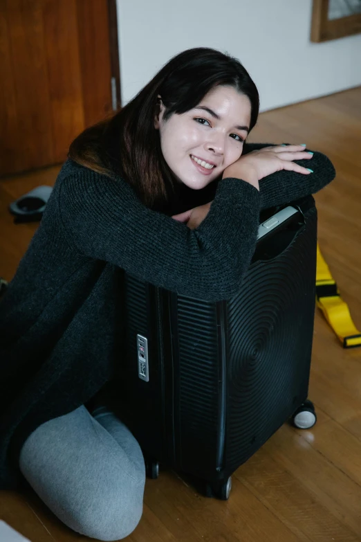 a girl is posing on the floor with her suitcase