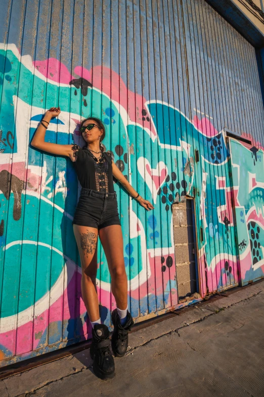 woman in high cut black shorts poses against a painted wall