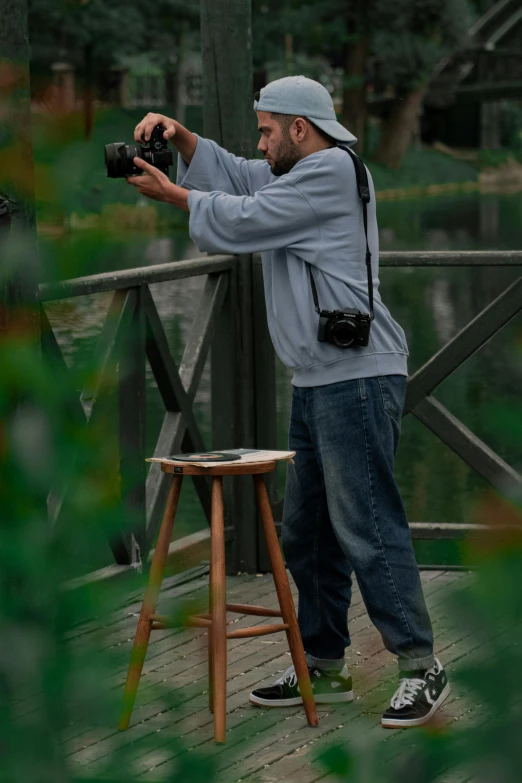 a man holding up a camera and using a stool