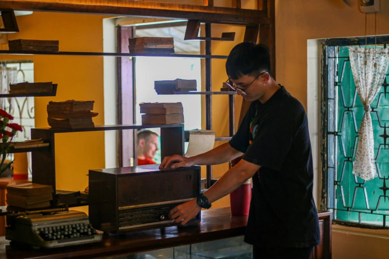 a man with glasses stands in front of an old fashioned typewriter