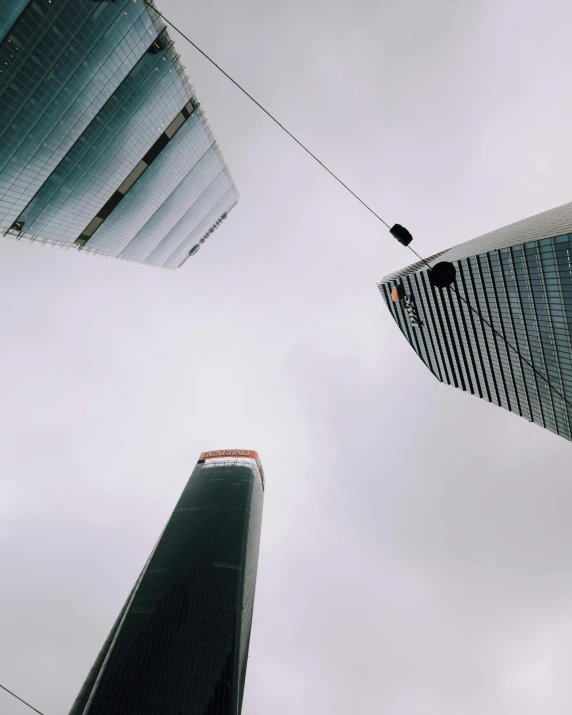 two skyscrs in a cloudy sky, one with a rope