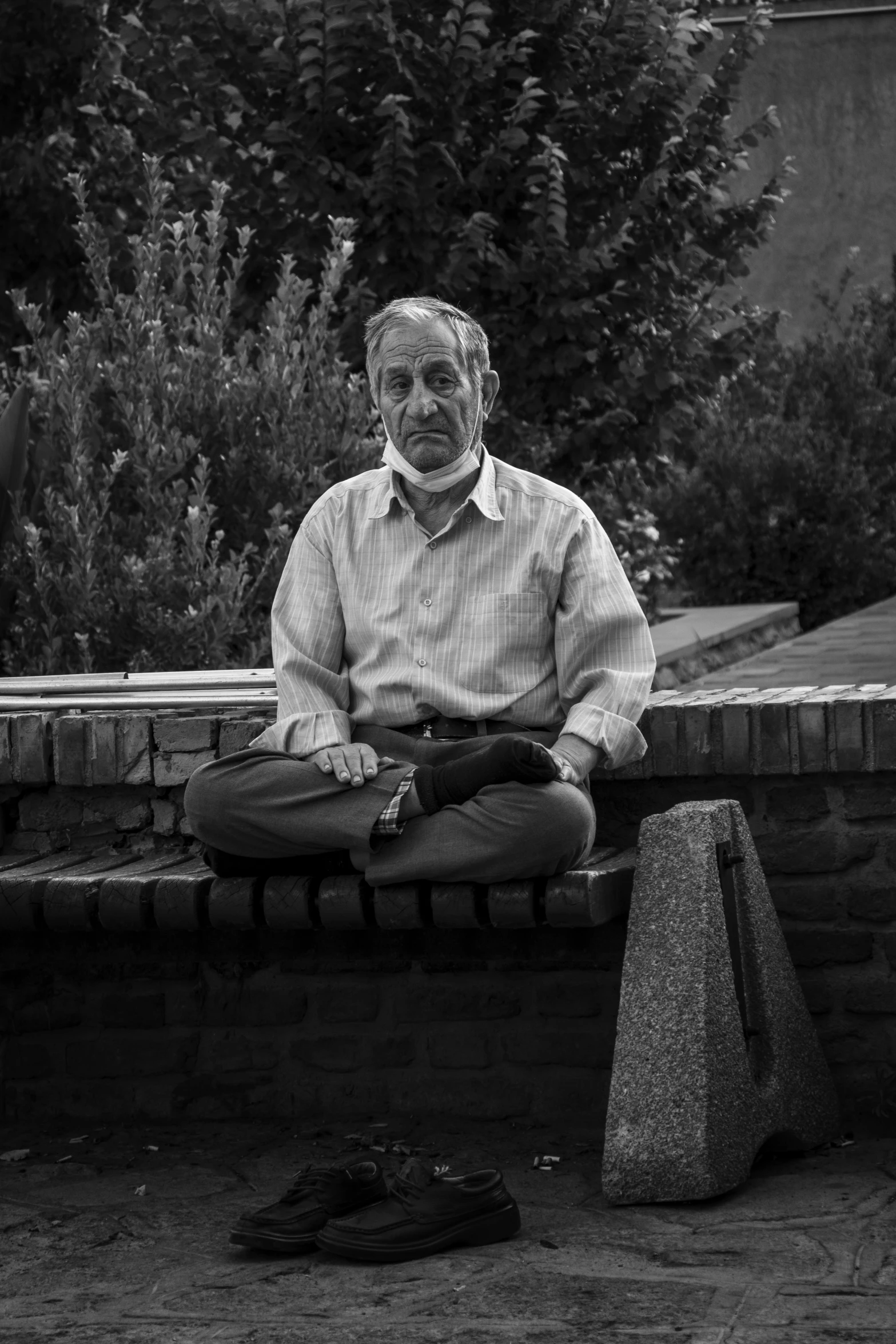 a black and white po of an old man sitting on a bench