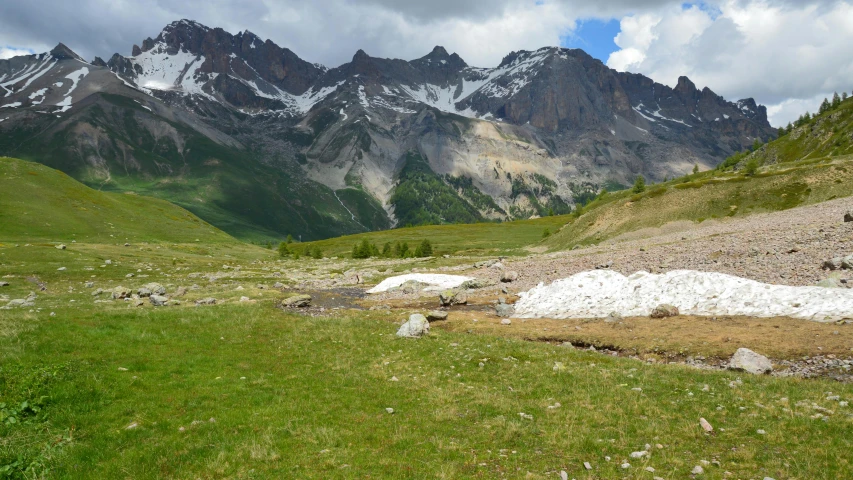 a small stream running through a valley filled with grass