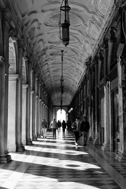 several people walking down a hallway with stone pillars