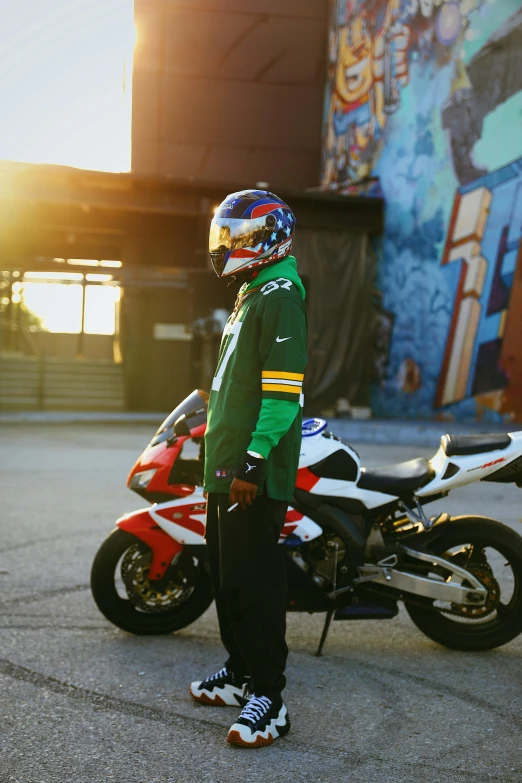 the  wearing a motorcycle helmet standing beside his parked motorcycle