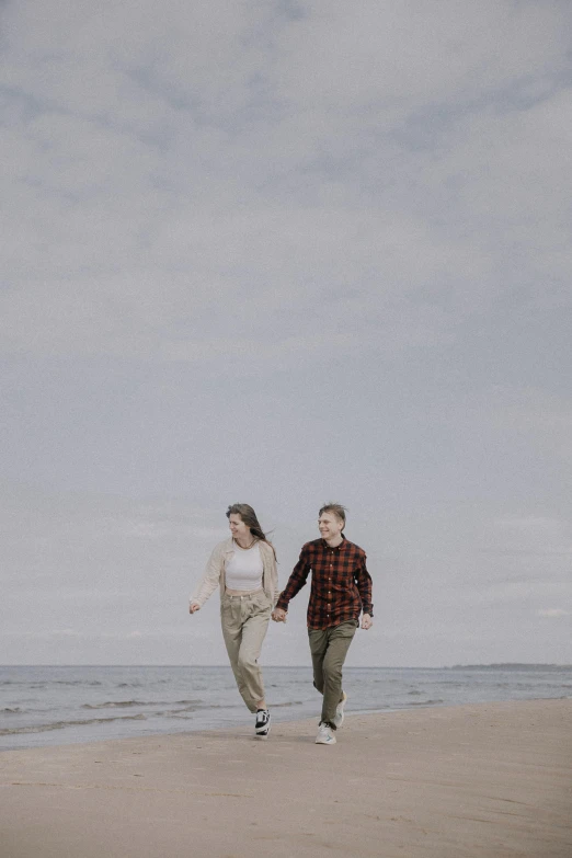 two people run on the beach holding hands