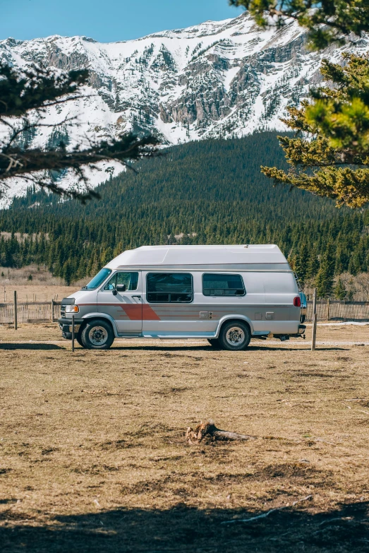 a van is parked in the field next to trees