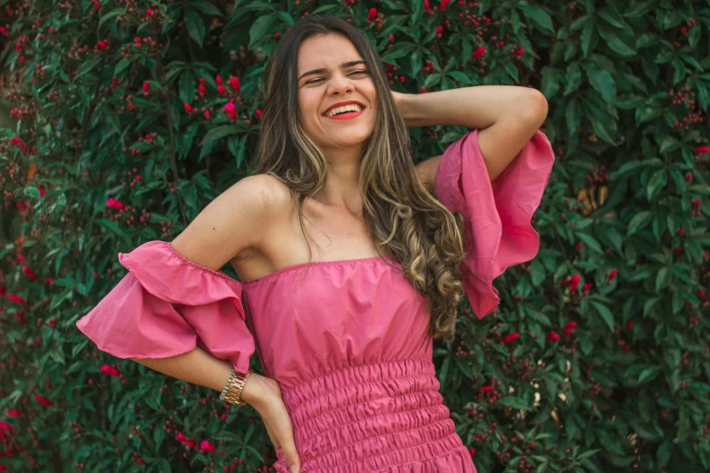 woman in pink dress with red flowers on shrubbery background