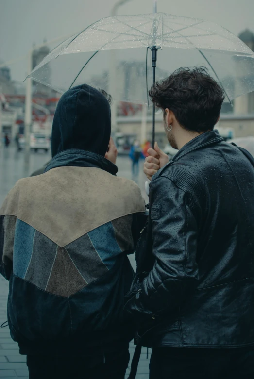 two people stand under an umbrella while talking