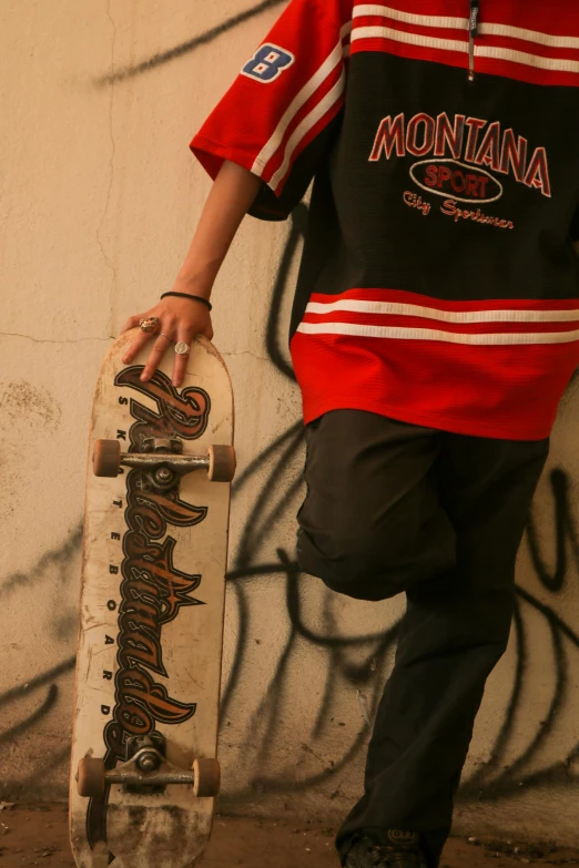 person standing with skateboard in front of wall