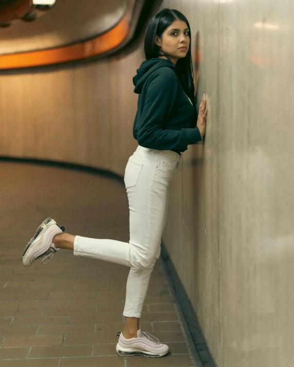 a young woman leaning against a wall near a wall