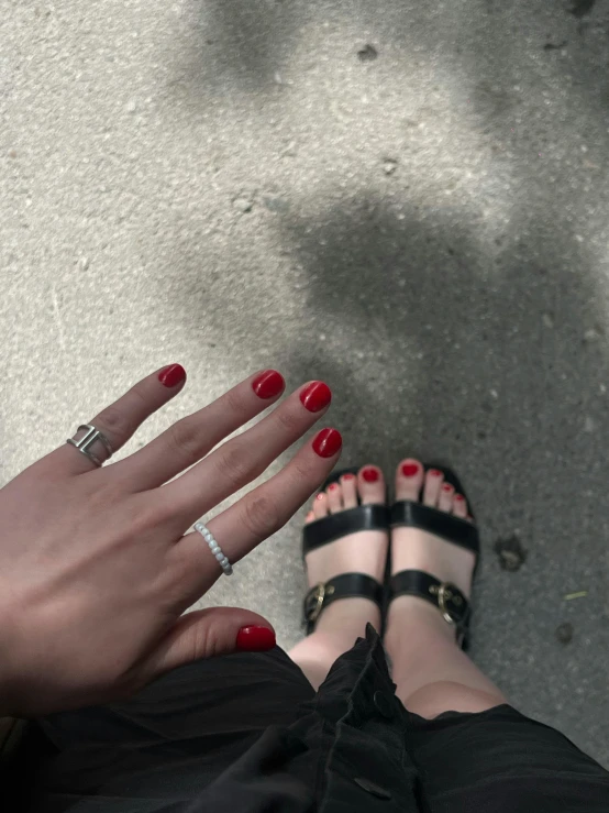 woman with red and black nails standing next to a white building