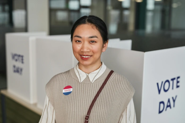 a woman is standing in front of a voting day sign