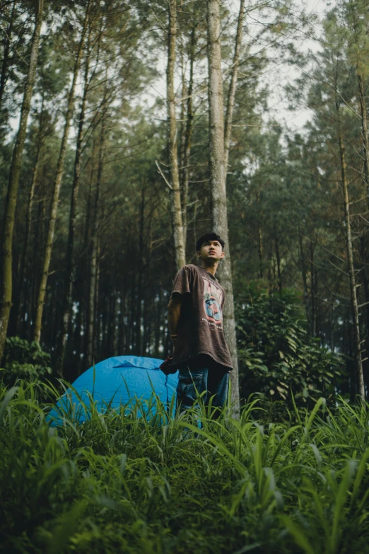 man standing in tall brush holding a blue object