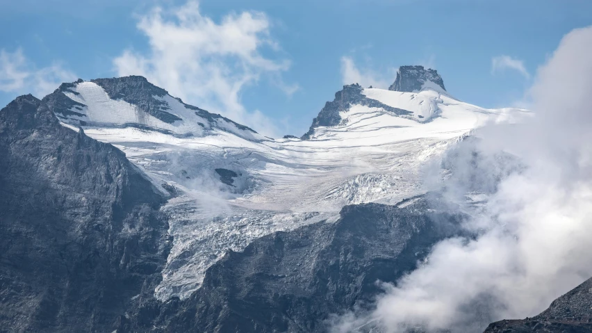 snow covered mountains with clouds in the foreground