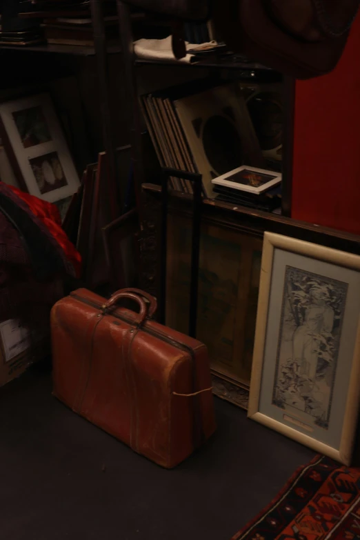 a brown suitcase sitting on a carpet next to picture frames