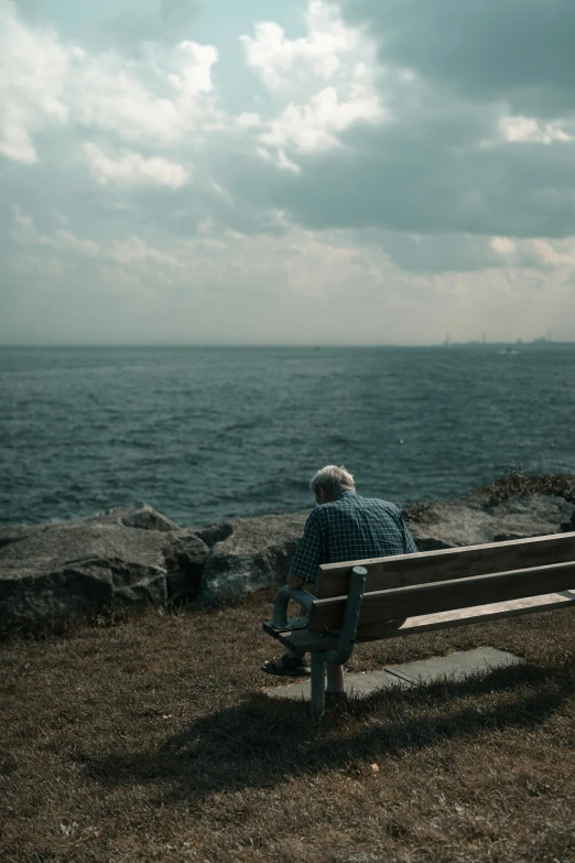 a man sits on a bench next to the ocean