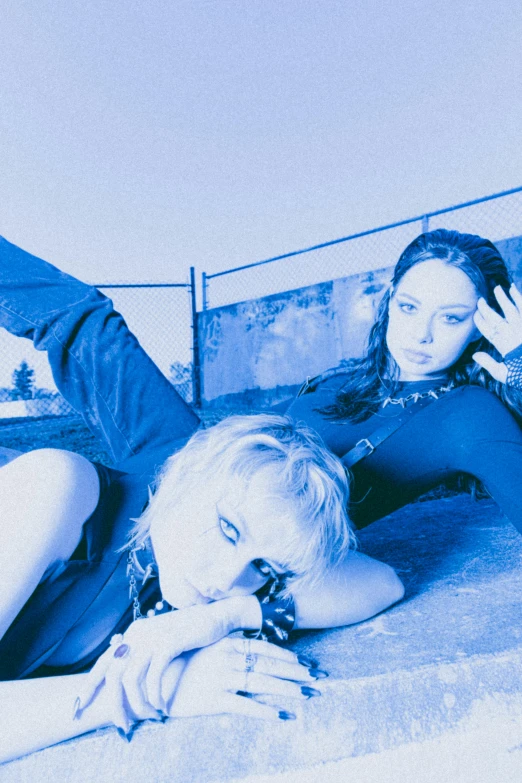 two woman laying down looking at the back of a bus