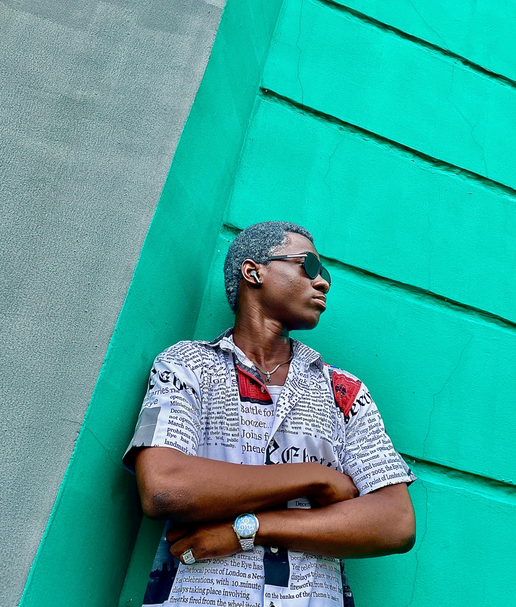 a man wearing sunglasses standing against a wall