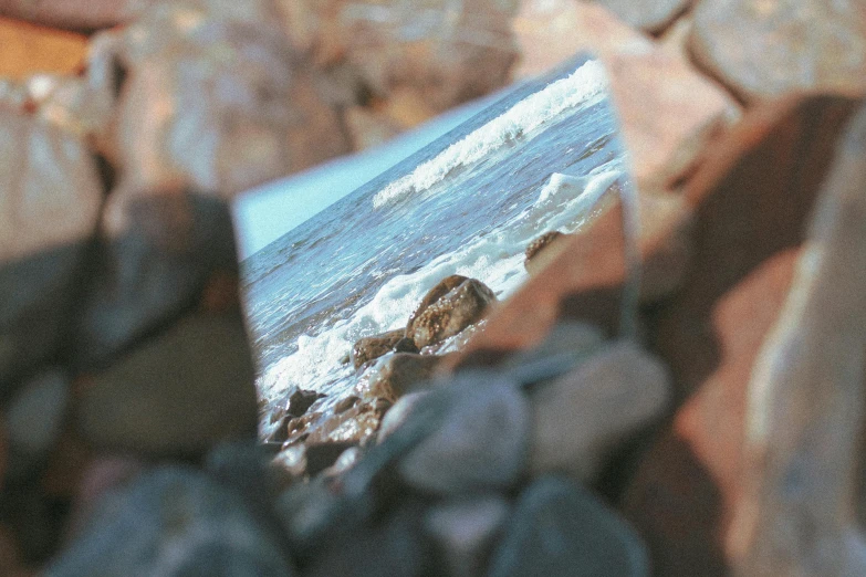 a broken mirror is shown on rocks at the beach