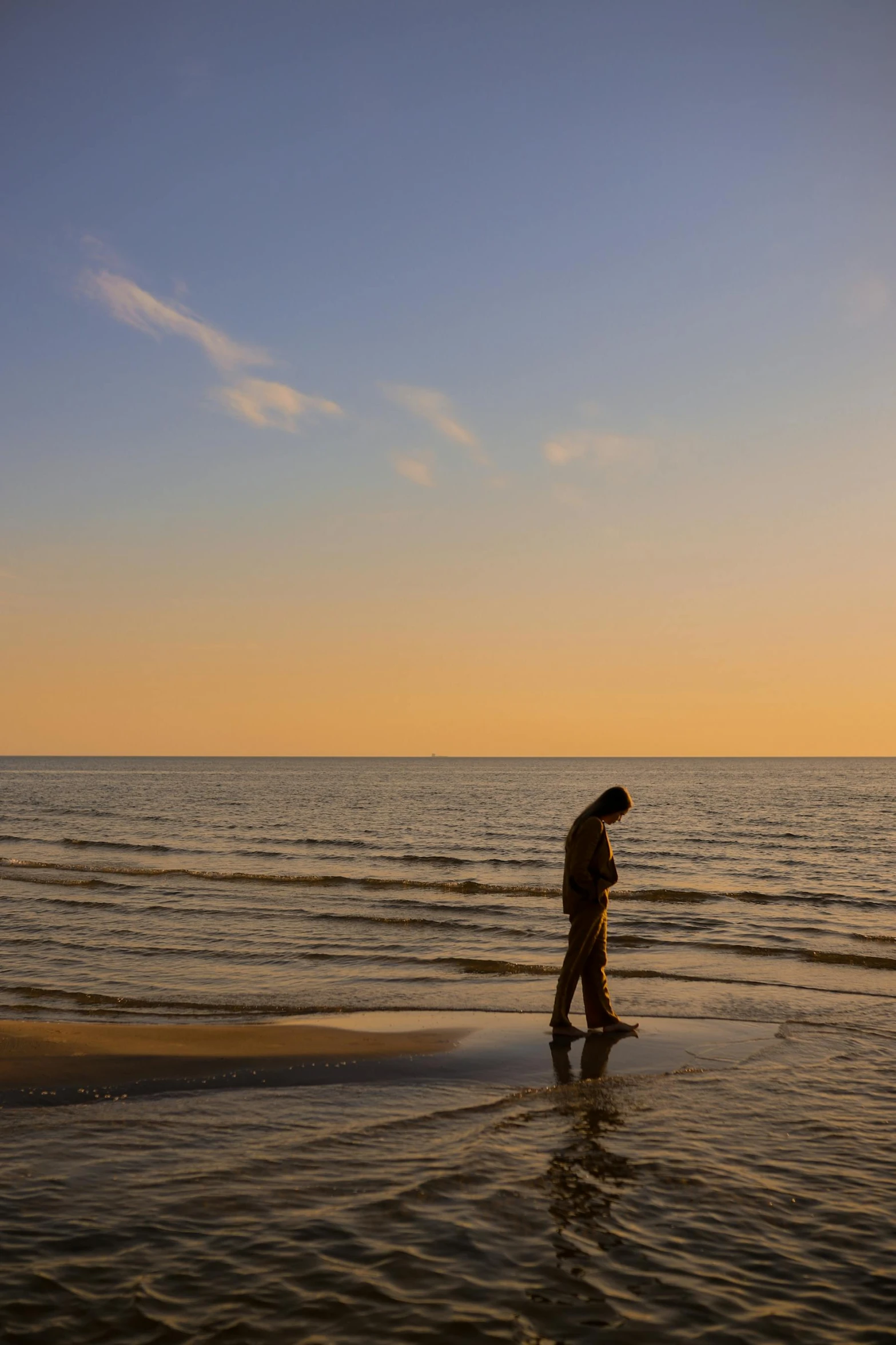 a man is walking across the water at sunset