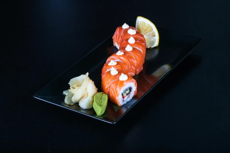 sushi with fish and vegetables on a black plate