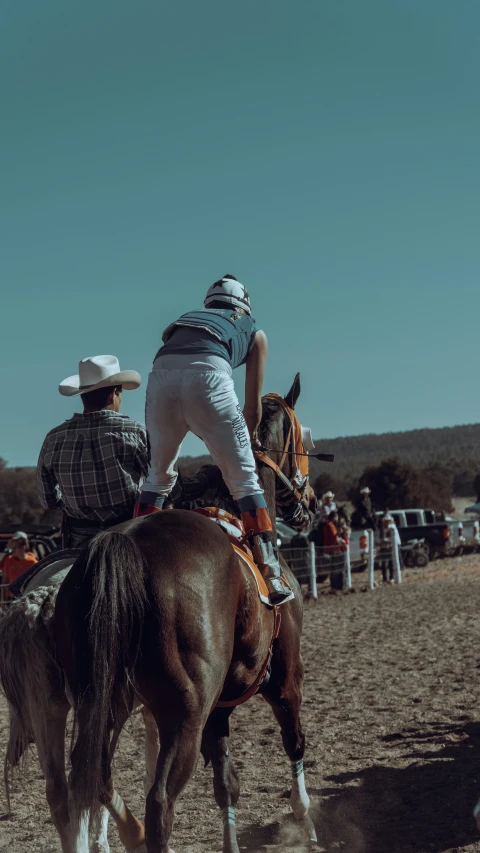 two men sitting on horses watching other people at a rodeo