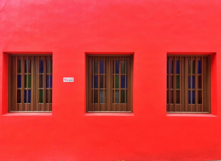 three windows in front of a red wall