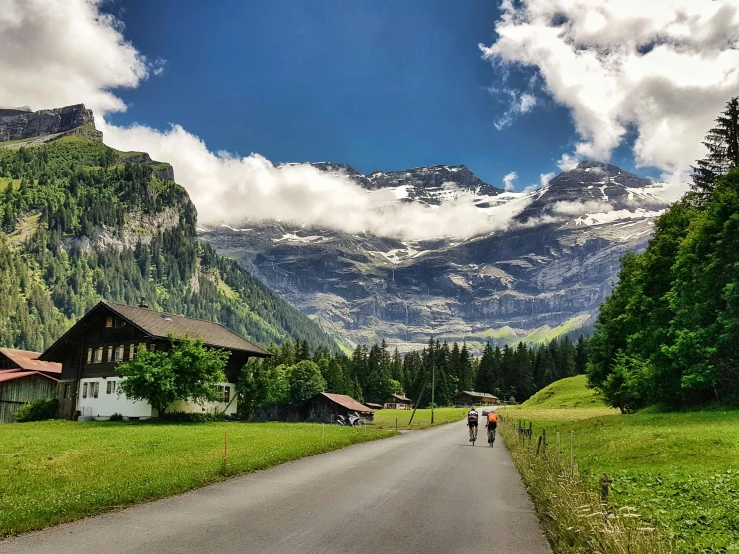 two people walk down the road near a mountains range