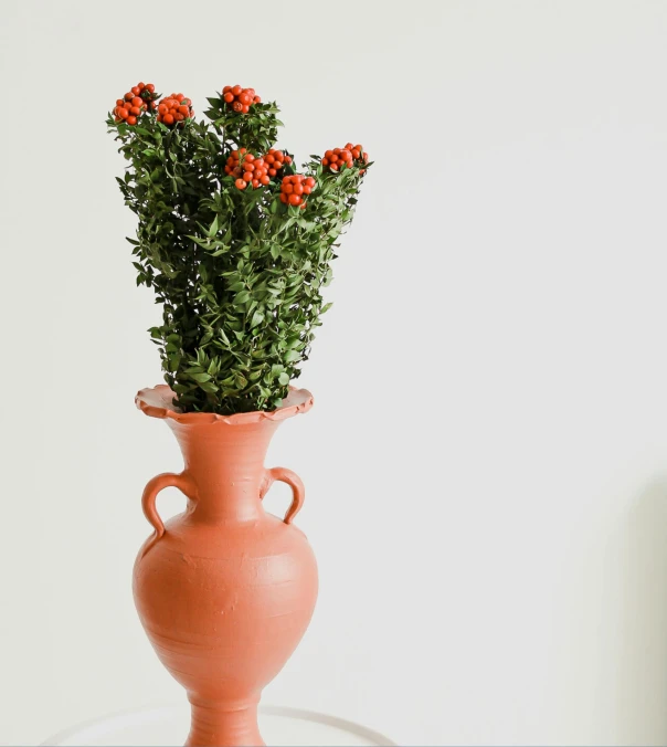 an orange vase with some red flowers in it